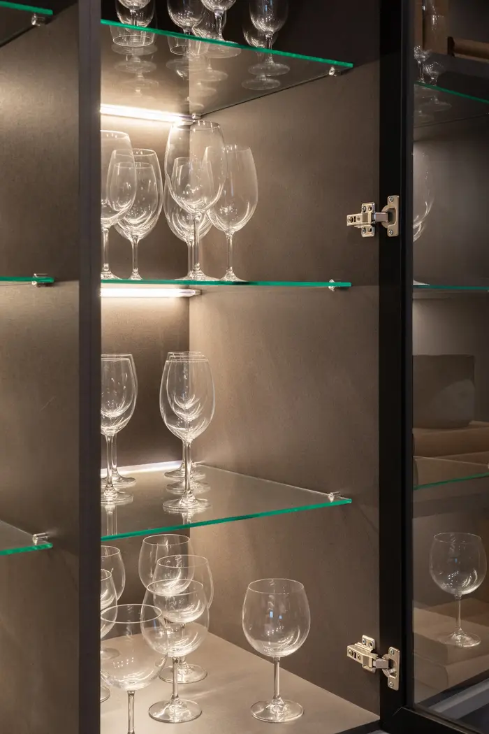 Prateleiras de vidro com taças e iluminação